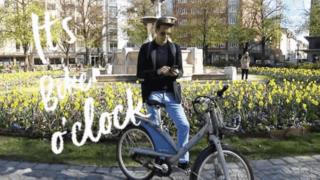 a man riding a bike in a park with the words " it 's time o ' clock " written in white