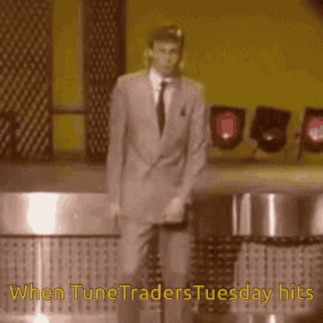 a man in a suit and tie is dancing with the words when tunetraders tuesday hits behind him