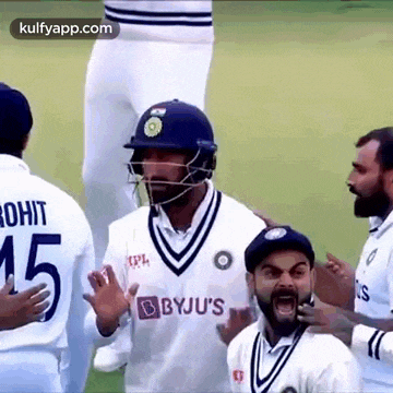 a group of cricket players are standing on a field . one of the players is wearing a helmet .