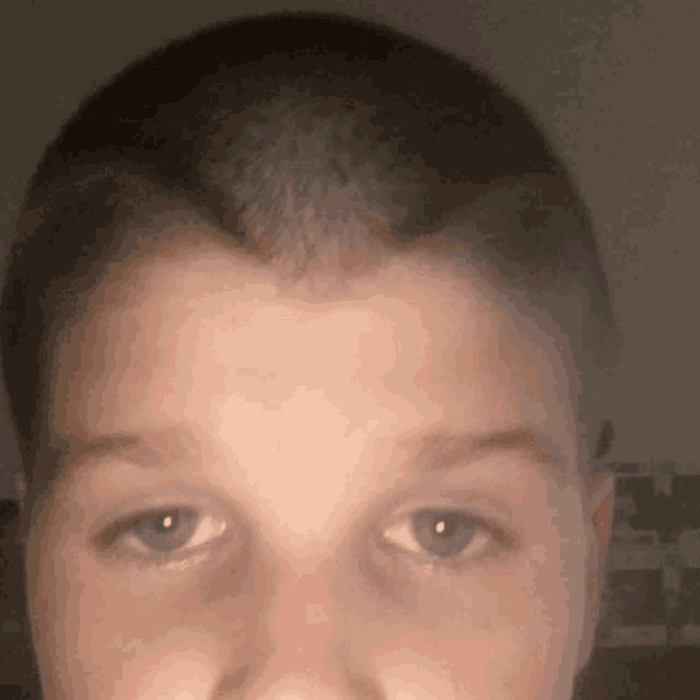 a close up of a young boy 's face with a shaved head