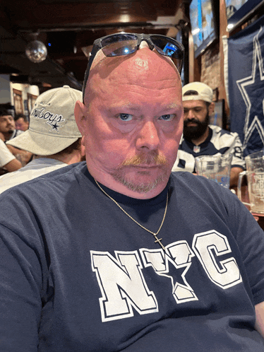 a man wearing a nyc t-shirt is sitting at a table