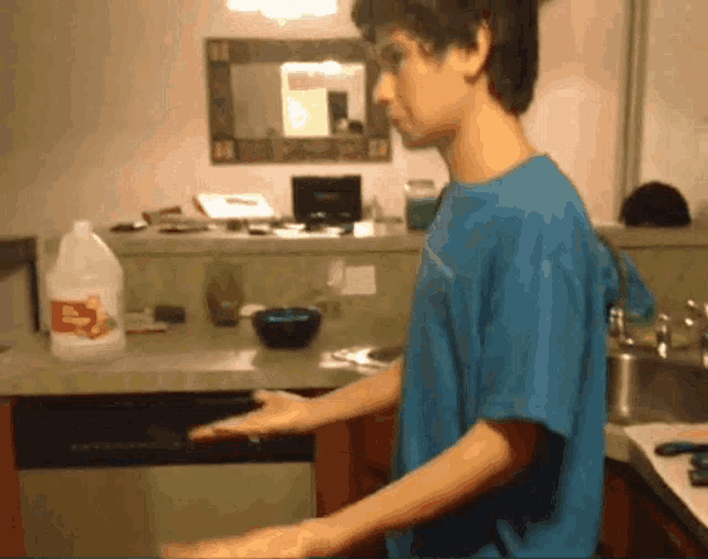 a man in a blue shirt is standing in front of a kitchen counter with a gallon of apple cider vinegar on it