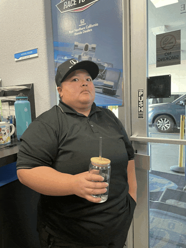 a woman standing in front of a honda dealership holding a drink