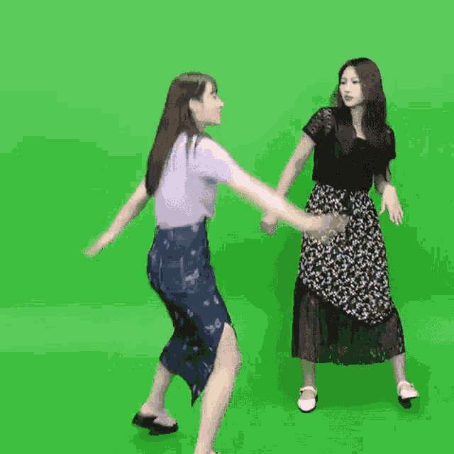 two women are dancing together on a green screen