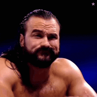 a shirtless wrestler with a beard and long hair