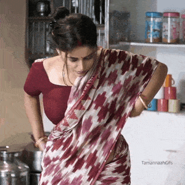 a woman in a red and white striped saree is standing in a kitchen with tamannahgifs written on the bottom