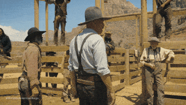 a group of men are standing around a wooden fence with horizon american saga written on the bottom of the image