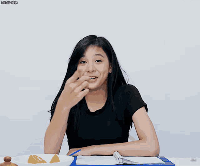 a girl in a black shirt is sitting at a table with a clipboard and a bowl of lemon slices