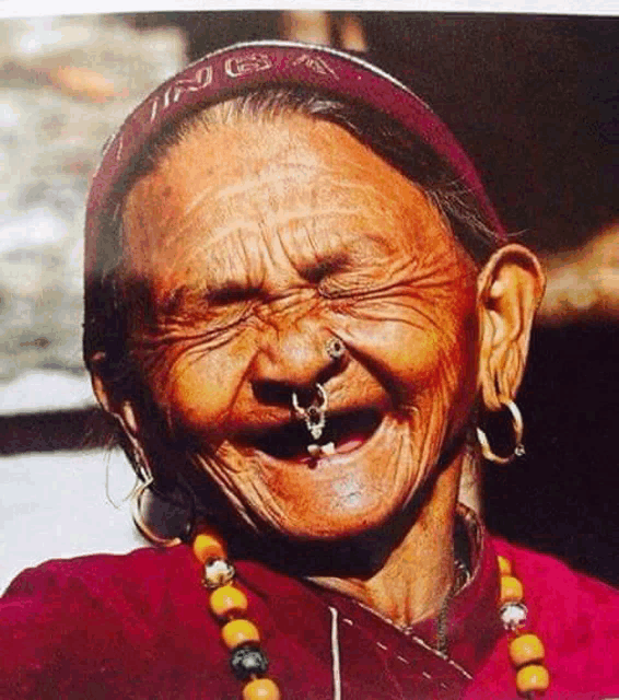 an older woman with a nose ring and earrings is smiling