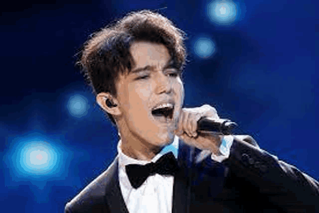 a man in a tuxedo is singing into a microphone .