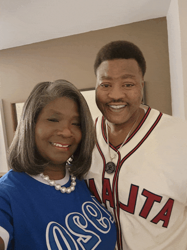 a man wearing a jersey that says atlanta is posing with a woman