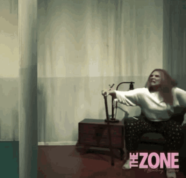 a woman is sitting in a chair with the word zone on the bottom right