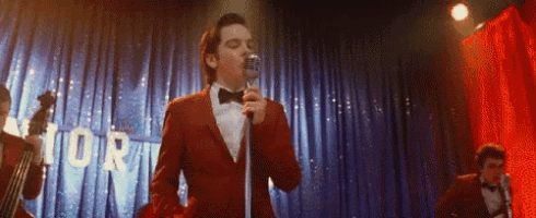 a man in a red suit singing into a microphone on a stage .