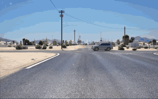 a silver suv is driving down a desert road with mountains in the background