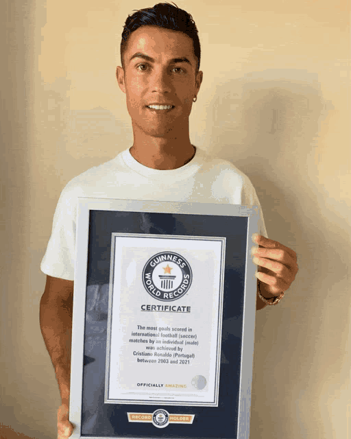 a man in a white shirt is holding a certificate from the guinness world records