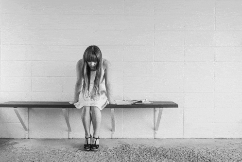 a black and white photo of a woman sitting on a bench .