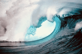 a large wave in the ocean with a blue sky behind it