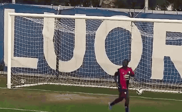 a man in a red shirt is running towards a soccer goal in front of a sign that says euor