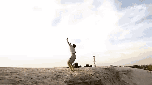 a man is doing a handstand on top of a sand dune with the words awesome on the bottom right