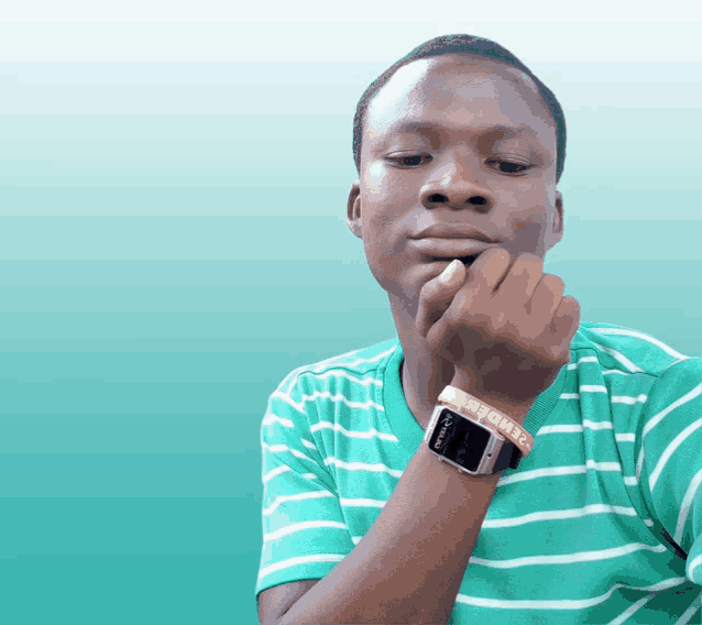 a young man wearing a green and white striped shirt has a watch on his wrist with the word barbie on it