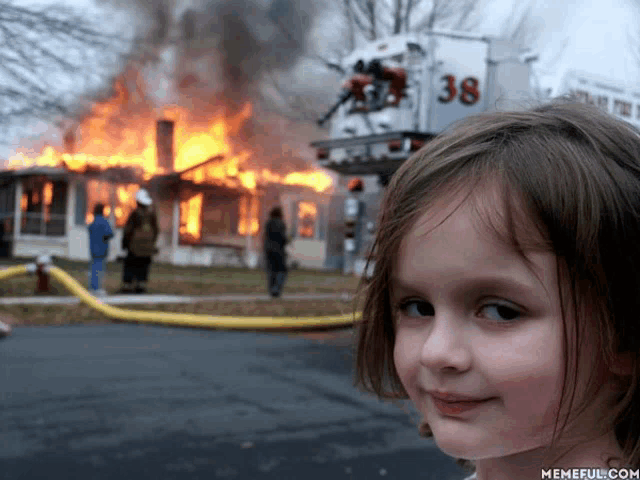 a little girl stands in front of a burning house with a fire truck number 38 in the background