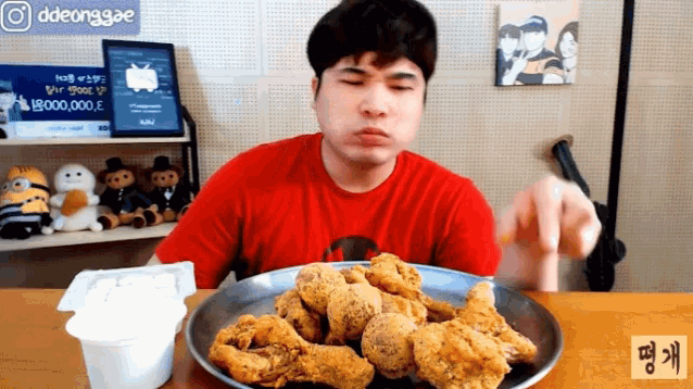 a man sitting at a table with a plate of fried chicken and a sign that says ddeonggae on it