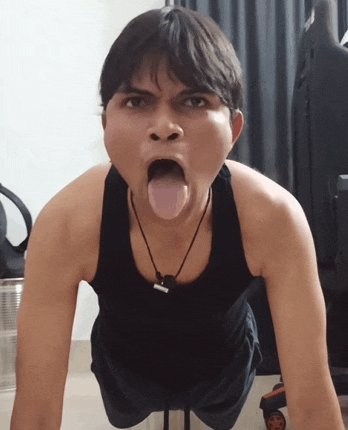 a man in a black tank top is doing push ups with his tongue hanging out