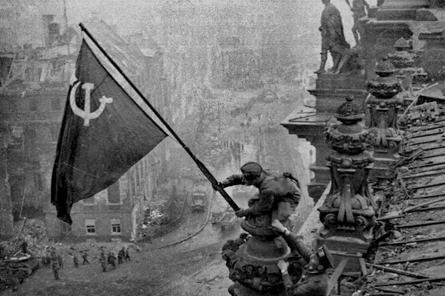 a black and white photo of a man raising a flag