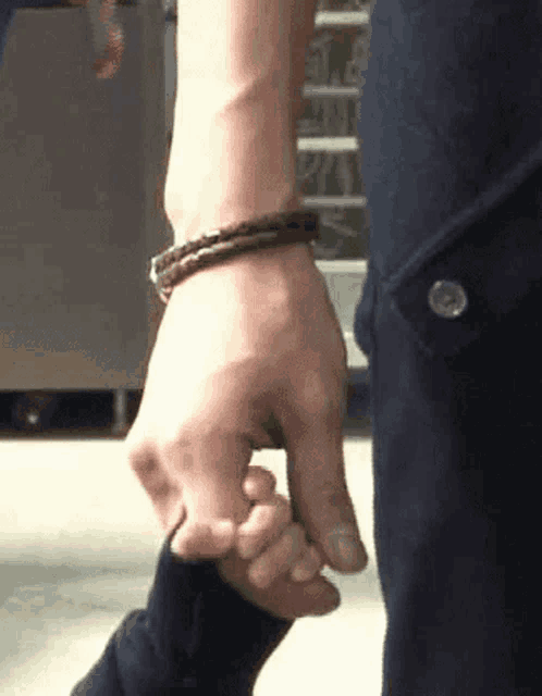 a person is holding another person 's hand while wearing a bracelet on their wrist .