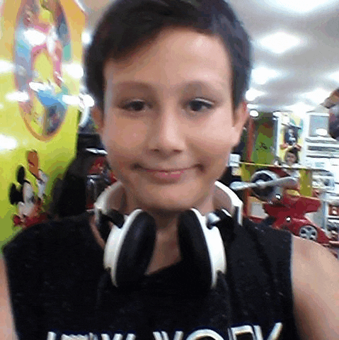 a young boy wearing headphones and a new york shirt smiles for the camera