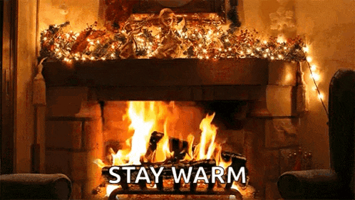 there is a fireplace with christmas lights on it and the words `` stay warm '' written in front of it .