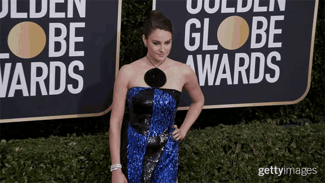 a woman in a blue and black dress is standing in front of a sign that says golden globe awards