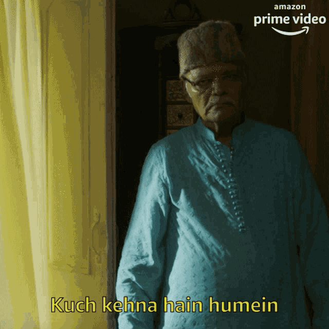 a man in a blue shirt is standing in front of a door with the words kuch kehna hain humein above him