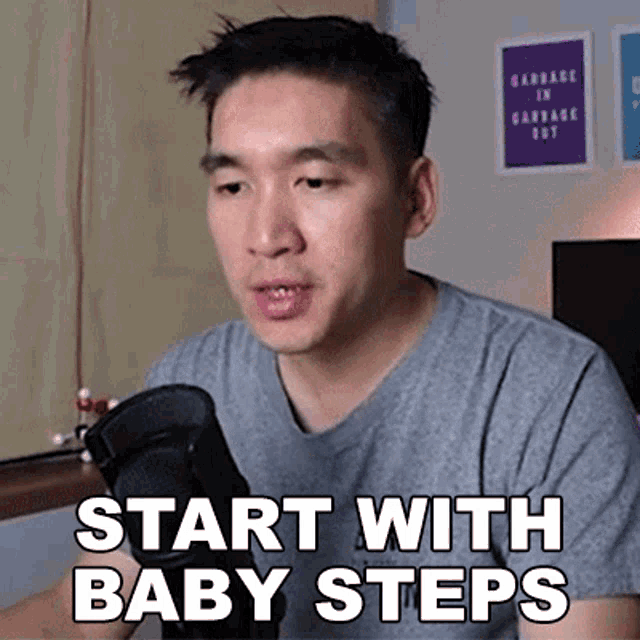 a man sitting in front of a microphone with the words " start with baby steps " on his shirt