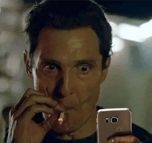 a man is smoking a cigarette and looking at his phone .