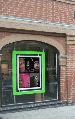 a brick building with a green frame with a picture on it