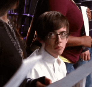 a young man wearing glasses is holding a piece of paper in his hand