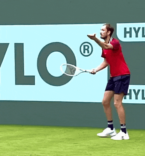 a man in a red shirt is holding a tennis racquet in front of a sign that says hyl on it