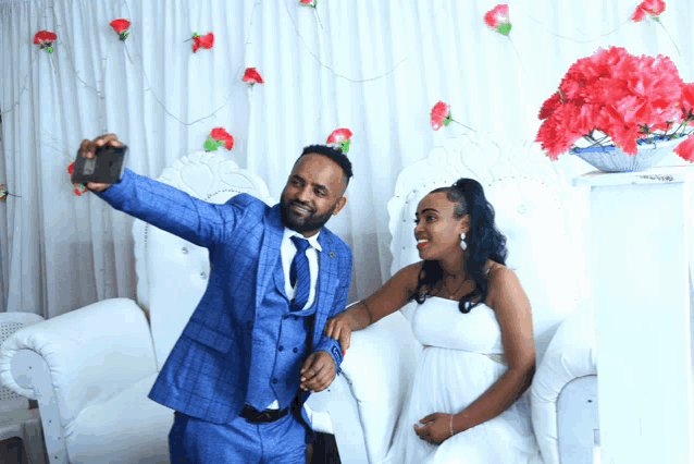 a man in a blue suit is taking a selfie with his phone