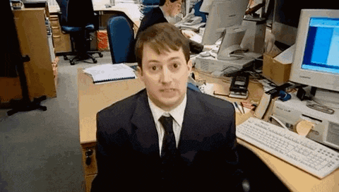 a man in a suit and tie is sitting at a desk in front of a computer in an office .