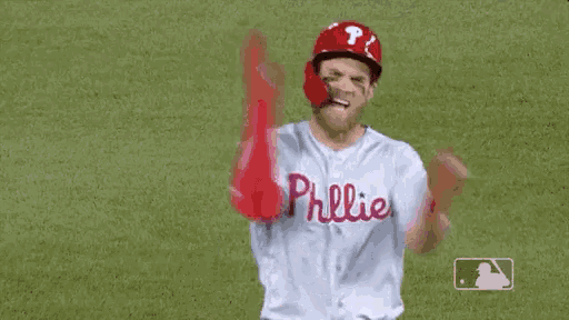 a baseball player is standing on a field with his arms in the air and wearing a phillies jersey .