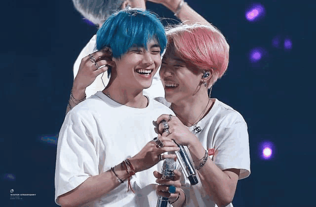 a man with blue hair and a woman with pink hair are laughing together