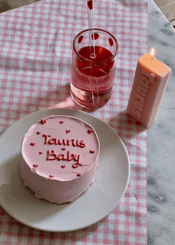 a taurus baby cake sits on a plate next to a candle