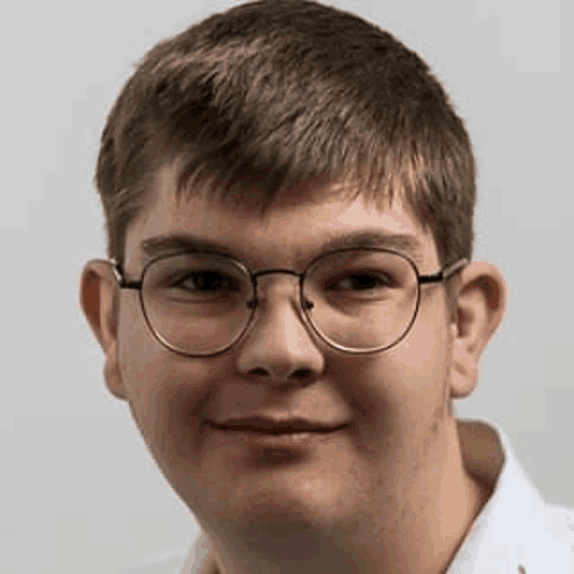 a close up of a young man wearing glasses and a white shirt .