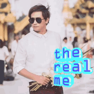 a man wearing sunglasses is holding a bouquet of flowers with the words " the real me " behind him