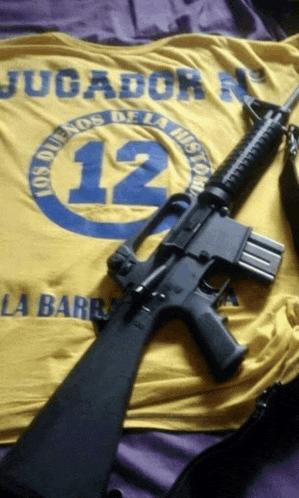 a gun laying on a yellow shirt that says jugador 12