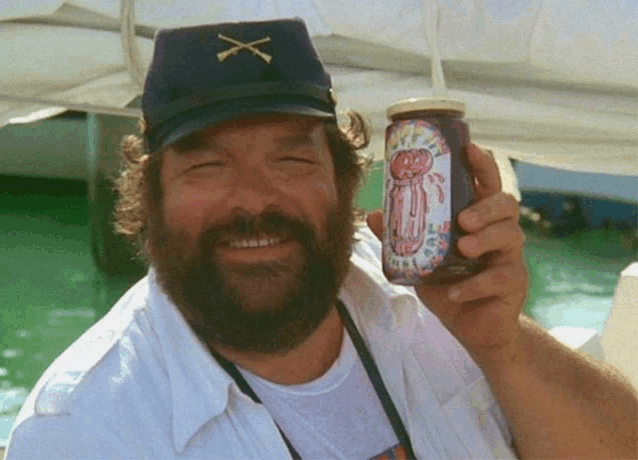 a man with a beard wearing a hat with an x on it holds a jar of jam