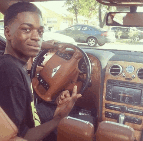 a young man is sitting in a bentley car giving the middle finger