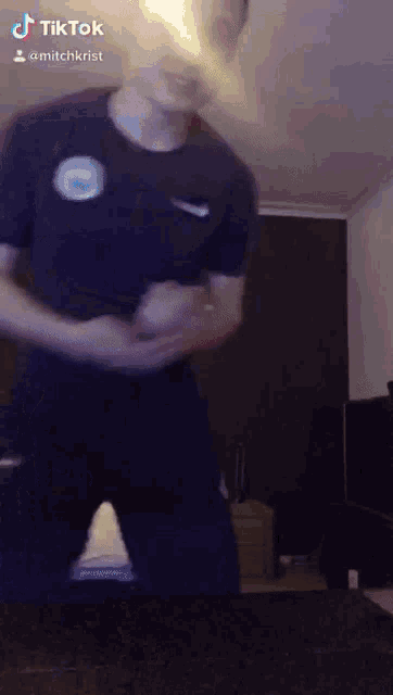 a man wearing a nike shirt is dancing in a room with a tiktok watermark