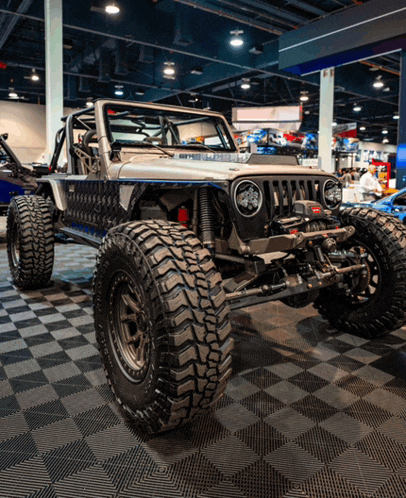 a silver jeep with big tires is on display